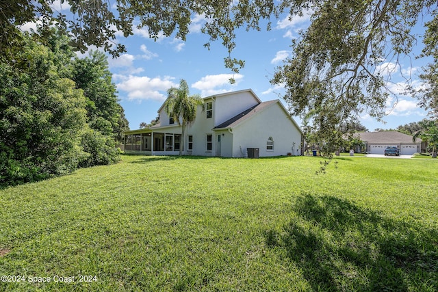 1290 Mercedes Dr, Merritt Island, FL 32952 - back of house with a sunroom, stucco siding, a yard, and central AC