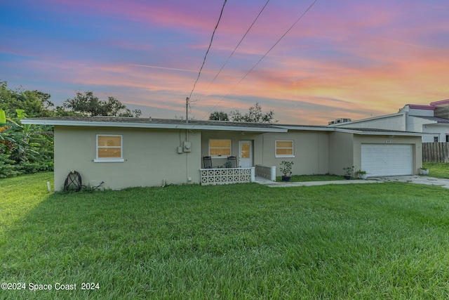 single story home with a yard, covered porch, and a garage