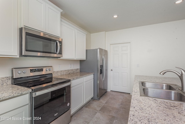 kitchen featuring white cabinetry, appliances with stainless steel finishes, light stone countertops, and sink