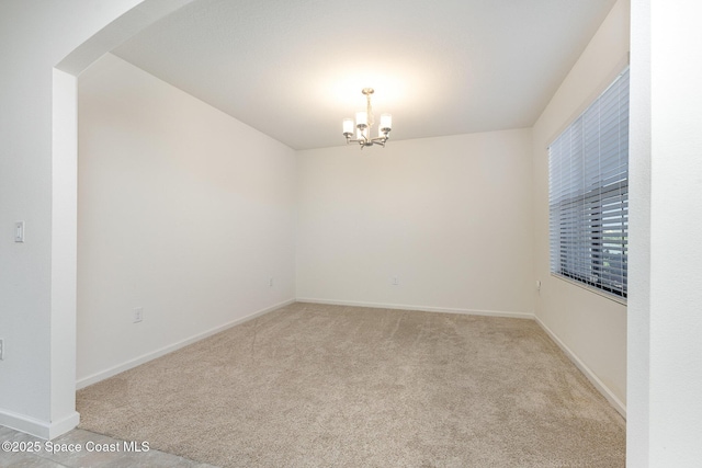 unfurnished room with light colored carpet and an inviting chandelier