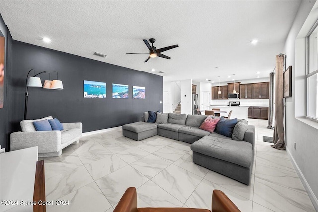 living room with a textured ceiling and ceiling fan