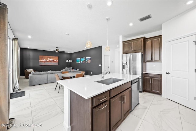 kitchen featuring a kitchen island with sink, sink, hanging light fixtures, stainless steel appliances, and ceiling fan