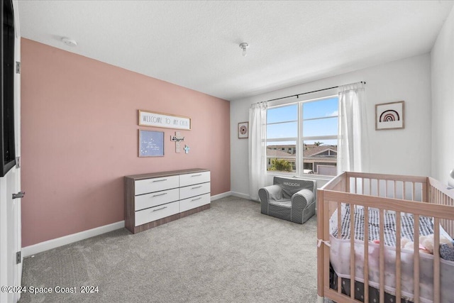 carpeted bedroom featuring a crib and a textured ceiling