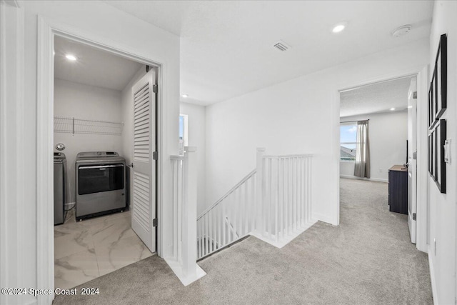 corridor featuring separate washer and dryer and light carpet