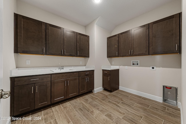 laundry area with hookup for a washing machine, a textured ceiling, electric dryer hookup, cabinets, and sink