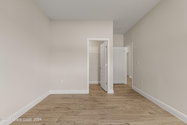 unfurnished bedroom with light hardwood / wood-style floors, a walk in closet, and a closet