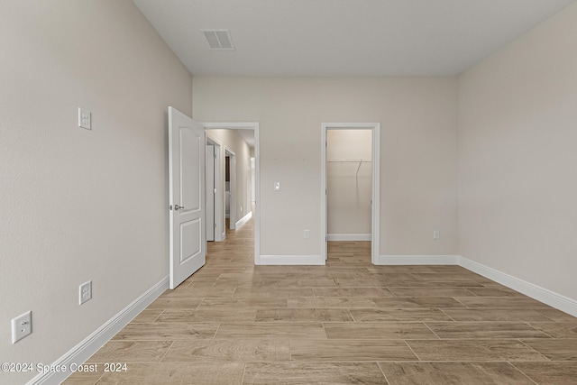 unfurnished bedroom with a spacious closet, light hardwood / wood-style floors, and a closet