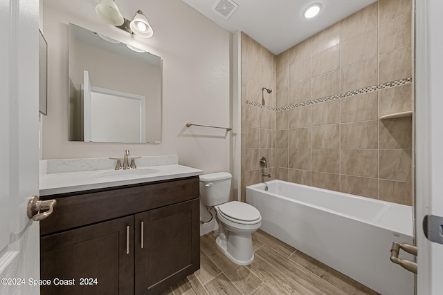 full bathroom featuring tiled shower / bath, vanity, and toilet