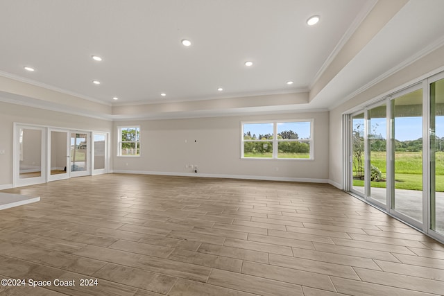 unfurnished living room with light wood-type flooring, a healthy amount of sunlight, and crown molding