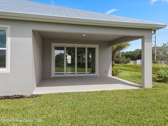 view of exterior entry with a patio and a yard