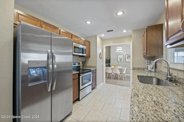 902 Beaverdale Ln, Rockledge, FL 32955 - kitchen featuring a sink, brown cabinets, stainless steel appliances, visible vents, and light stone counters