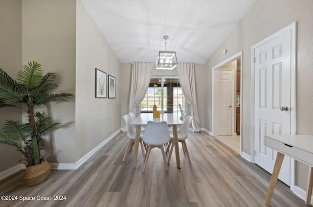 dining space featuring wood-type flooring and vaulted ceiling