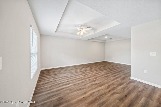 spare room featuring ceiling fan, a raised ceiling, and dark wood-type flooring