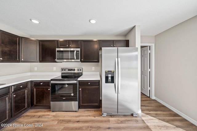 kitchen featuring dark brown cabinets, light wood-type flooring, and stainless steel appliances