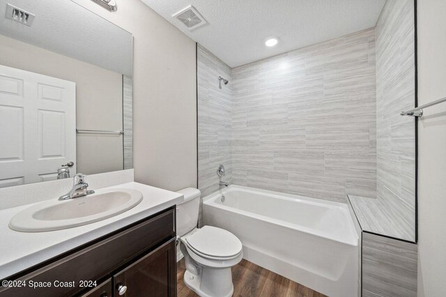 full bathroom featuring vanity, tiled shower / bath, toilet, a textured ceiling, and wood-type flooring