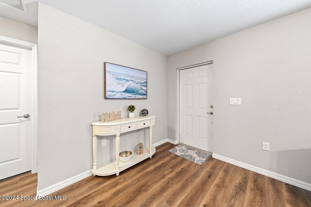 foyer entrance featuring a textured ceiling and dark wood-type flooring