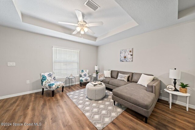 living room featuring hardwood / wood-style floors, a textured ceiling, a tray ceiling, and ceiling fan