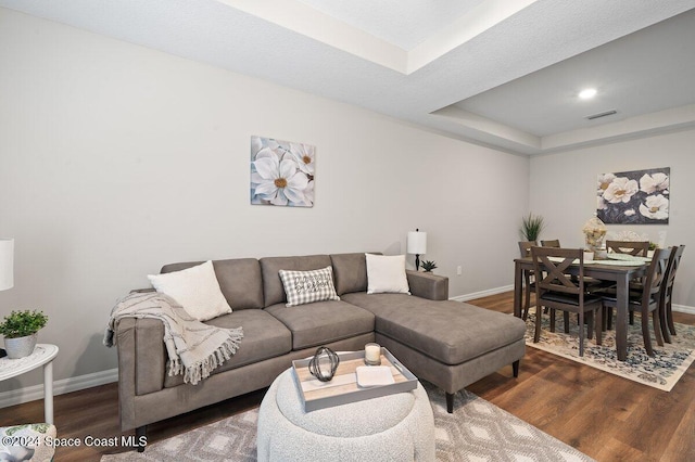 living room with dark hardwood / wood-style floors and a tray ceiling