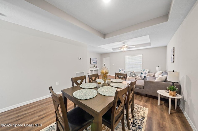 dining area with a tray ceiling, ceiling fan, a textured ceiling, and dark hardwood / wood-style floors