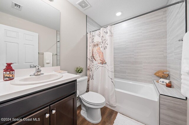 full bathroom with shower / bath combo, wood-type flooring, a textured ceiling, toilet, and vanity