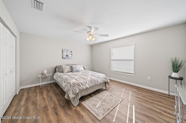 bedroom with dark hardwood / wood-style flooring, ceiling fan, and a closet