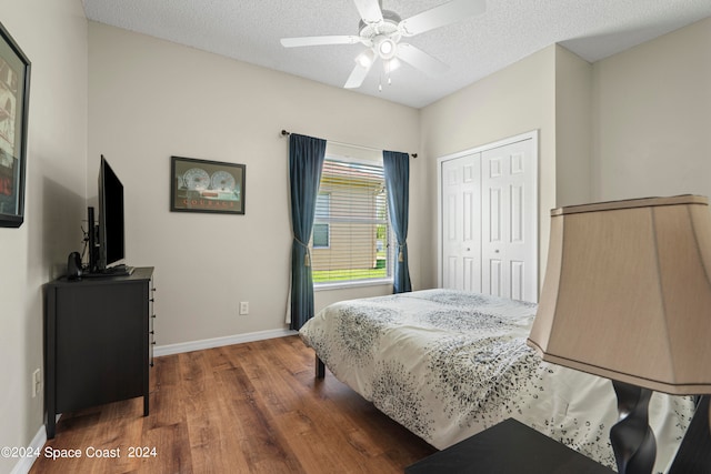 bedroom featuring dark wood-type flooring, a textured ceiling, ceiling fan, and a closet