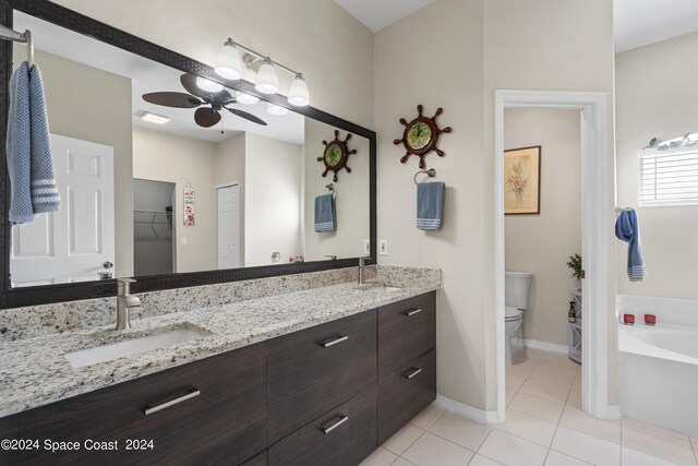 bathroom with vanity, ceiling fan, toilet, a bath, and tile patterned floors