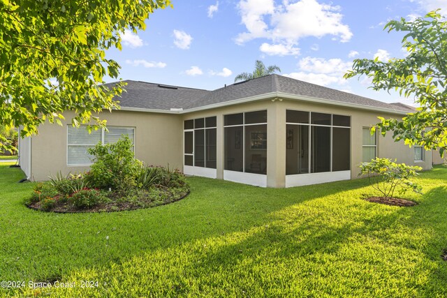 rear view of house featuring a yard and a sunroom