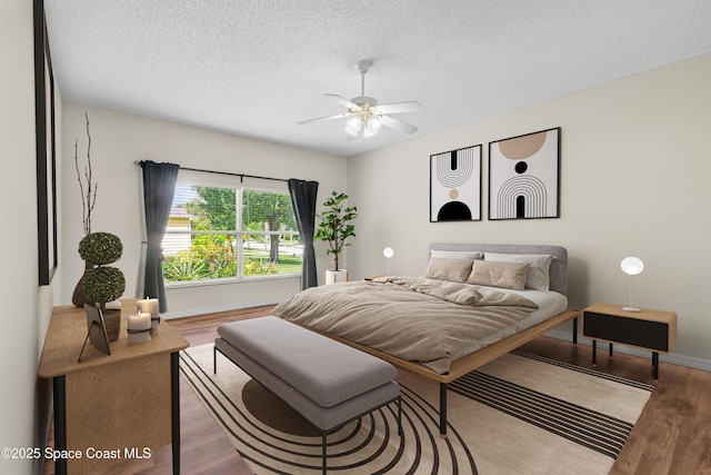 bedroom with light wood-type flooring, a textured ceiling, and ceiling fan