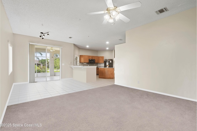 unfurnished living room with ceiling fan, light colored carpet, and a textured ceiling