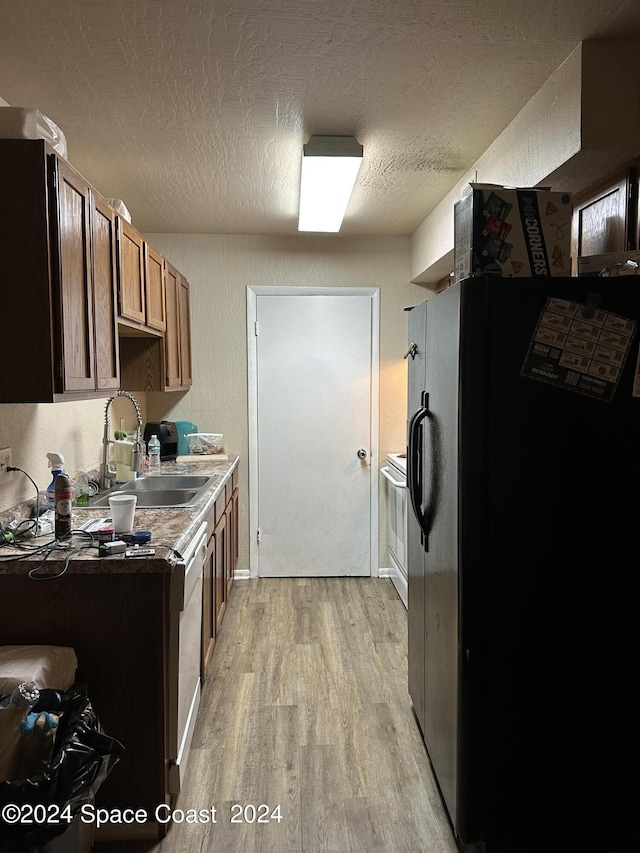 kitchen with sink, a textured ceiling, light hardwood / wood-style flooring, stainless steel fridge with ice dispenser, and dishwasher