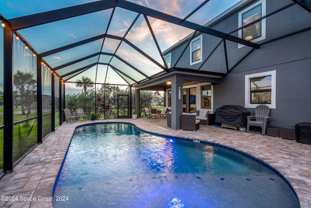 pool at dusk featuring a patio, an outdoor living space, and a lanai