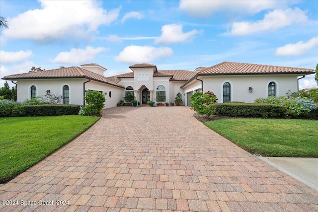 mediterranean / spanish-style home featuring a front yard and a garage