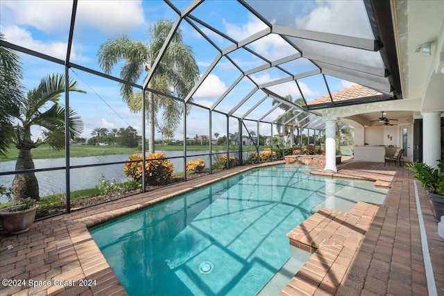 view of pool with ceiling fan, glass enclosure, a water view, and a patio area