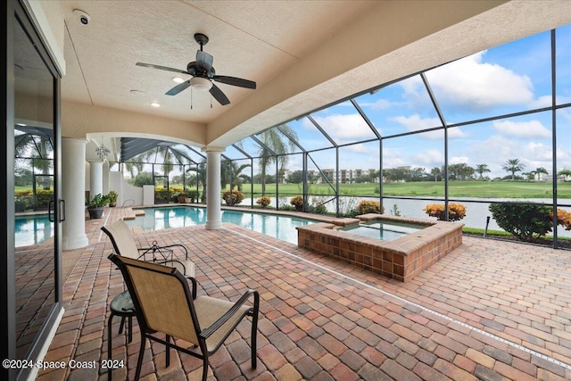 view of pool featuring an in ground hot tub, a water view, a lanai, ceiling fan, and a patio area