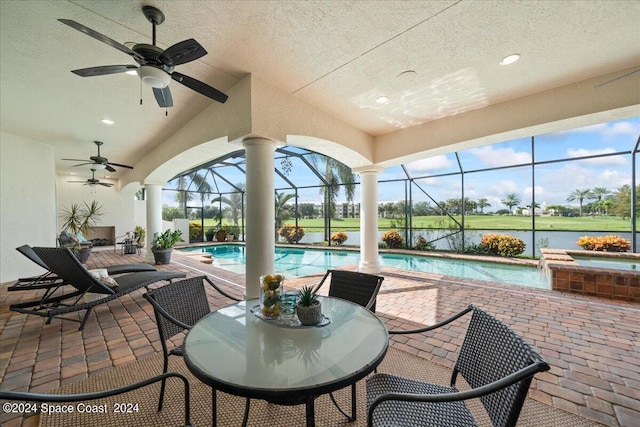 view of patio featuring a lanai, a water view, and ceiling fan