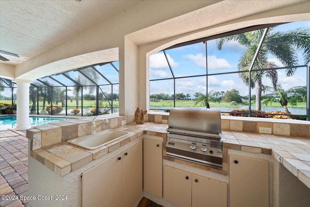 view of patio / terrace with exterior kitchen, glass enclosure, area for grilling, and sink