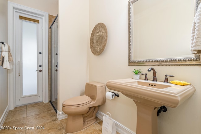 bathroom featuring a shower with door, toilet, and tile patterned floors