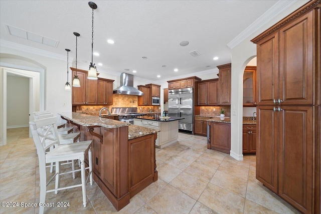 kitchen featuring hanging light fixtures, dark stone countertops, backsplash, wall chimney exhaust hood, and high quality appliances