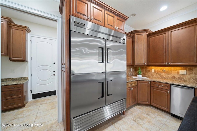 kitchen with light tile patterned floors, tasteful backsplash, appliances with stainless steel finishes, light stone countertops, and crown molding