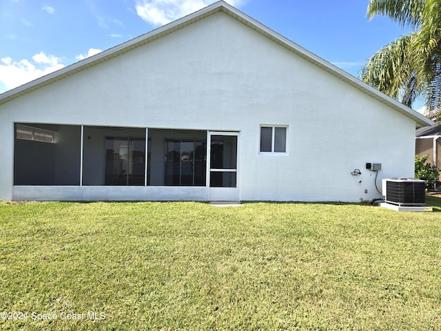 rear view of house featuring a sunroom, a lawn, and cooling unit