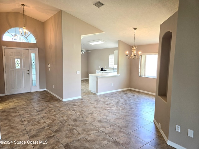 tiled entryway with a wealth of natural light, a textured ceiling, and an inviting chandelier