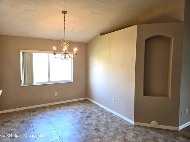 tiled empty room with an inviting chandelier and a textured ceiling