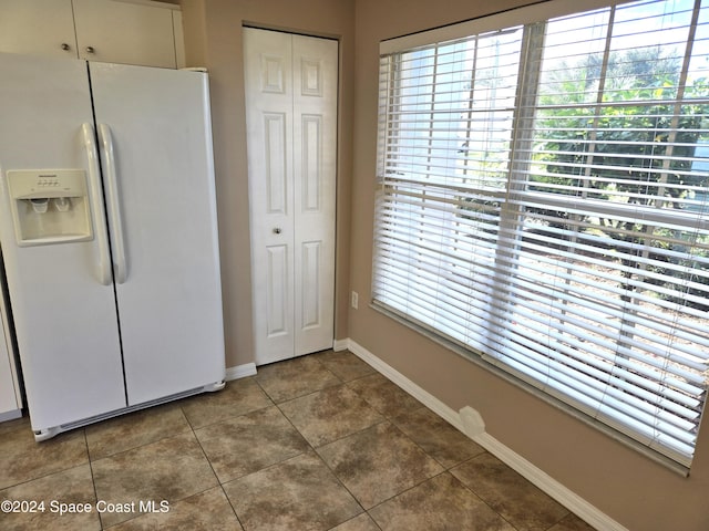 interior space with tile patterned floors and white fridge with ice dispenser