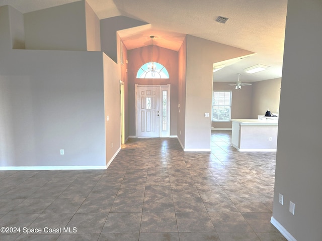 entrance foyer featuring ceiling fan, a textured ceiling, lofted ceiling, and dark tile patterned floors