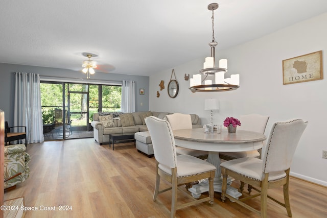 dining room featuring light wood-type flooring and ceiling fan with notable chandelier