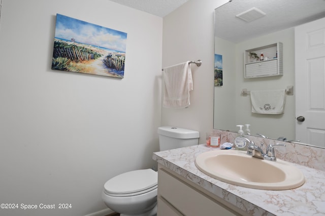 bathroom featuring a textured ceiling, vanity, and toilet