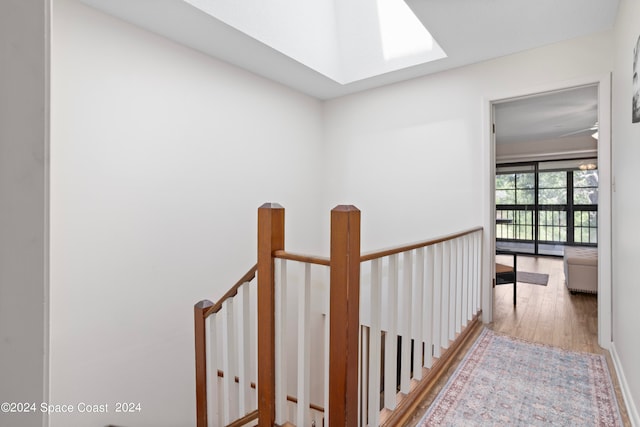 hall featuring wood-type flooring and a skylight