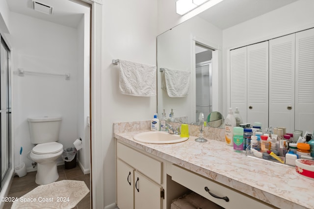 bathroom with vanity, tile patterned flooring, toilet, and a shower with door