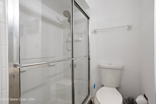 bathroom with a shower with door and toilet